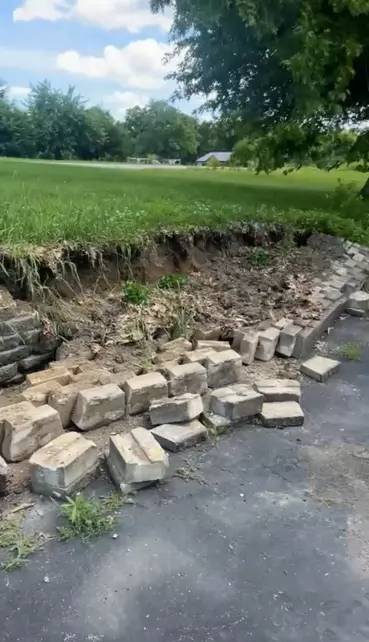 Collapsed retaining wall and driveway edge prepared for repair by Foil Land Services